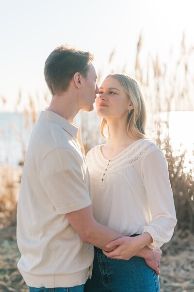 A woman nuzzles her fiance's nose as the sun sets behind them in New Haven. 
