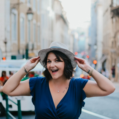 Joyful woman in a blue dress and sunhat smiling outdoors, representing confidence, freedom, and empowerment for women embracing a childfree life without guilt or societal pressure.