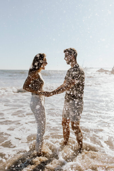 couple splashing water in the ocean on the beach
