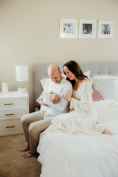 A new mother and father hold their newborn daughter during their newborn photography session in Madison WI.