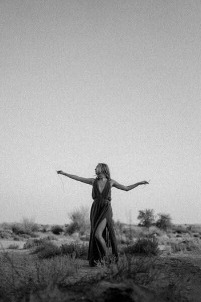 a young woman wearing a long dress standing in the desert