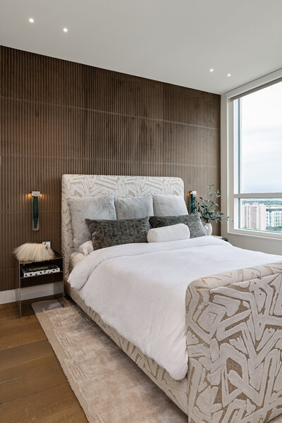 Wide shot of guest bedroom with warm textured wallpaper, patterned bedframe and layered bedding by Sister Studio.