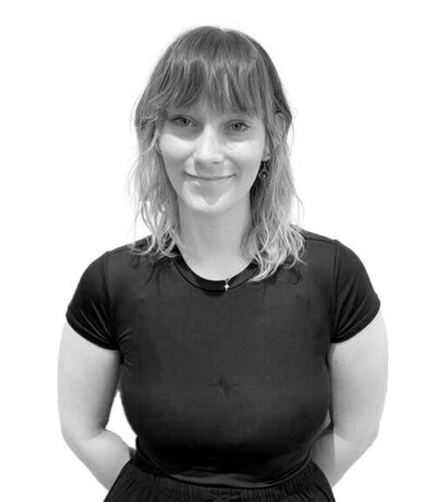 Apprentice with a sleek bun and sleeveless black top, radiating professionalism and eagerness to learn in the salon environment.