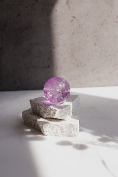 A high quality purple amethyst crystal sphere - our Endocrine ball, on a quartz slab.