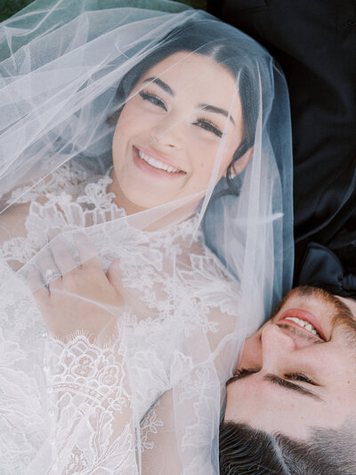 Fine art wedding photography capturing a romantic and dreamy moment of a bride and groom lying on the grass at a luxury wedding in Scottsdale Arizona.