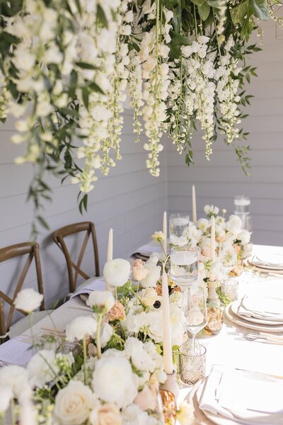 outdoor tablescape in white and peach with a hanging floral piece