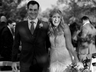 Black and white photo of bride and groom holding hands and smiling
