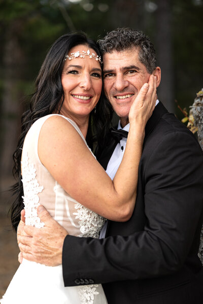 Bride and groom face to face looking at camera smiling.