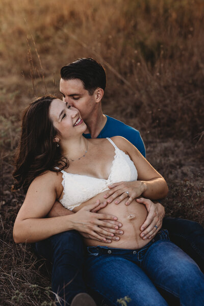 Pregnant woman and husband sitting on the grass