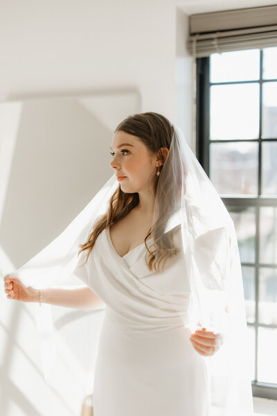 Bride looking away while holding veil
