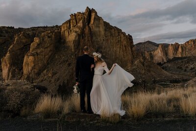 A wedding portait taken of a couple as she holds her dress in Smith  Rock State park
