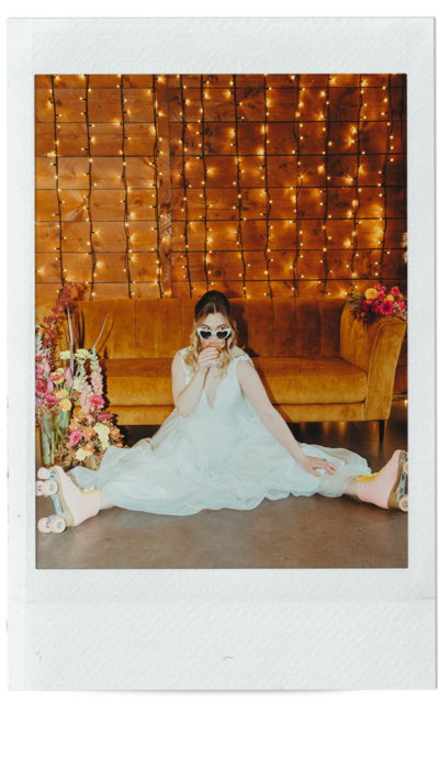 Bride sipping glass of champagne while sitting on the floor in her roller skates