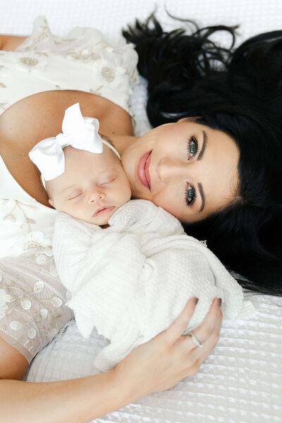 Mom holding newborn smiling up at camera
