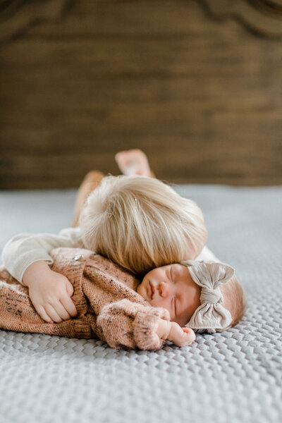 Baby brother hugging his newborn sister during a lifestyle newborn session.