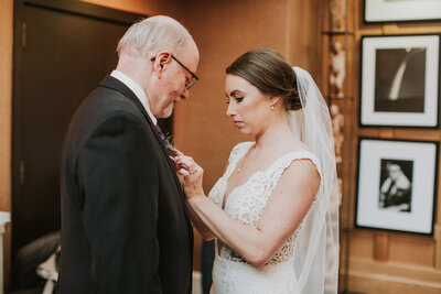 real bride wearing a custom bridal veil while pinning the boutonnière onto her father.