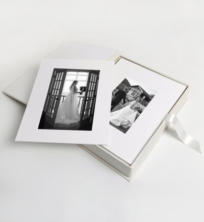 White matted photo prints of the bride and groom's wedding day in black and white prints with a custom wooden box.