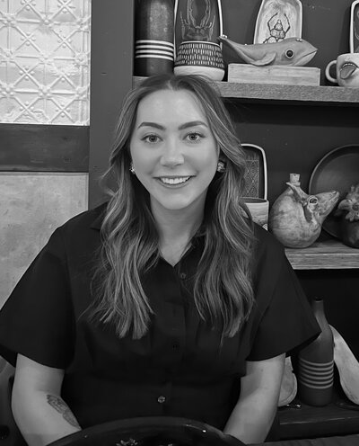 Black and white photo of woman with long, brown, wavy hair smiles at the camera.