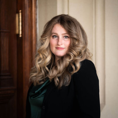 female attorney with big luscious curls satin green top and black suit jacket