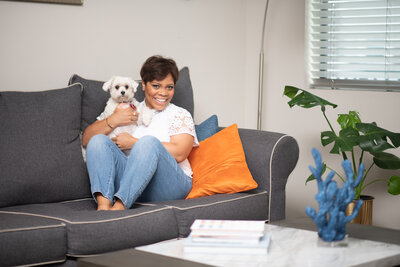 woman sitting on the couch holding a dog and smiling