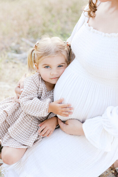 Image of big sister holding mother's expecting belly taken by Newborn Photographer Sacramento Kelsey Krall