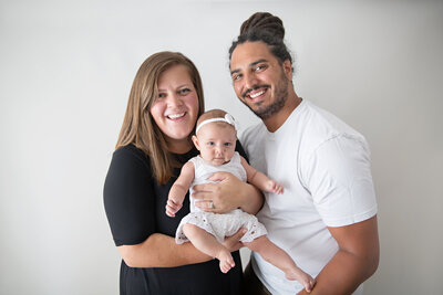 mom dad and baby white backdrop