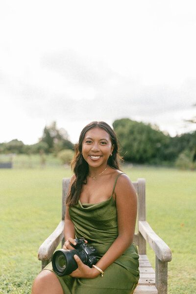 Emily Rohman photographer with green dress holding camera smiling at camera