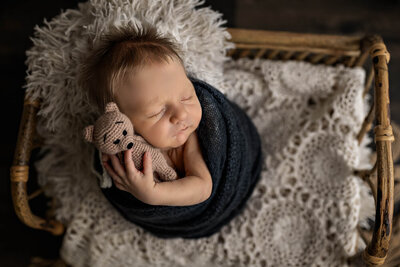 newborn baby wrapped hugging stuffed bear