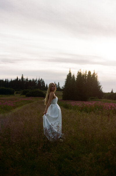 girl holding her dress as she runs through a field of flowers