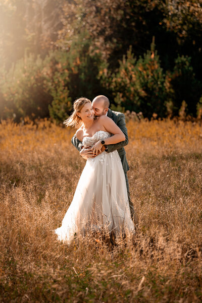 Couple tickling eachother in a field in the adirondack mountains with whiteface mountain as a backdrop
