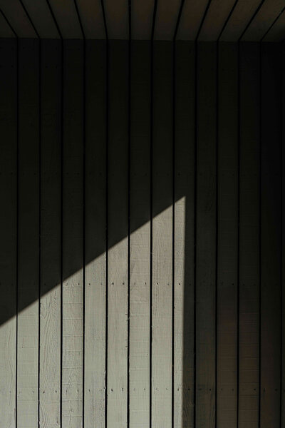 A wooden wall is photographed with harsh shadows at Kinclune House.