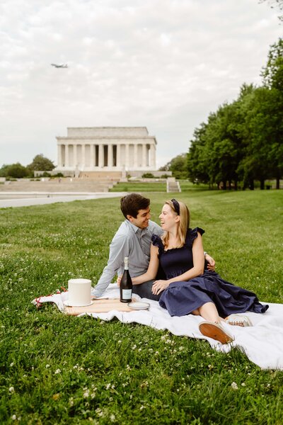 Couple sits on a blanket in the grass in front of the Lincoln Memorial on the National Mall in Washington DC