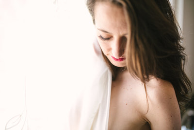 Woman hiding behind a curtain during boudoir session
