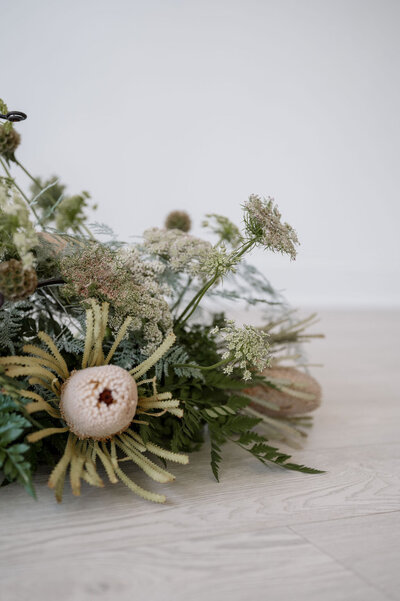 A close up of a floral arrangement Emily used for her brand shoot. It has lots of greenery and some neutral colored flowers.