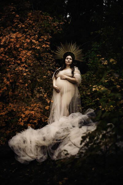 pregnant woman in fabric drape with headpiece with fall leaves photo