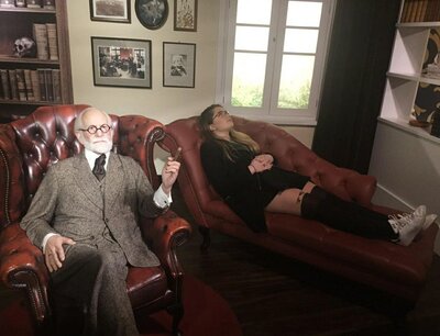 Founder laying of Freud's couch and a vax figure of Freud in front