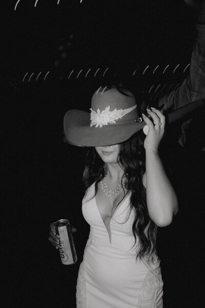 bride wearing grooms cowboy hat at wedding reception