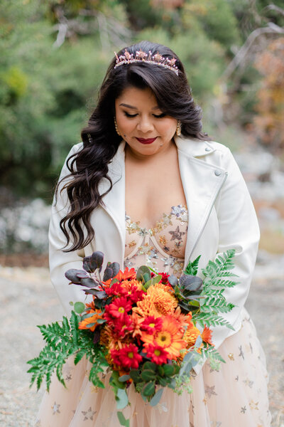bride looks down at her seasonal floral arrangement bridal bouquet