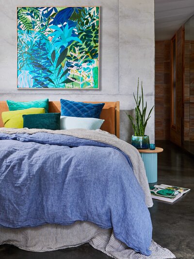 Colourful bedroom with blue bedding, green artwork, and layered styling by Melbourne interior stylist Hunter Interiors.