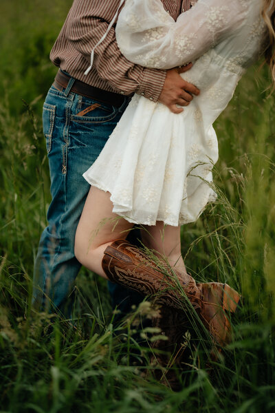 photo taken by a lifestyle photographer of a man and woman standing in a field while they embrace