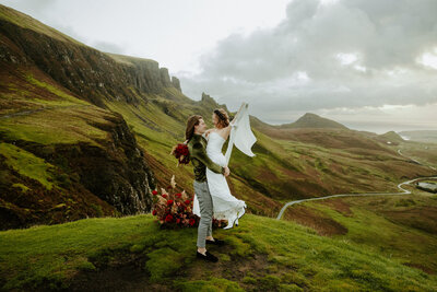 Adventurous bride wading through river in wedding dress during scotland elopemen