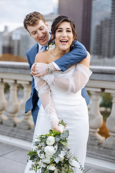 A carefree wedding couple embracing each other on the rooftop of the Philadelphia Free Library.