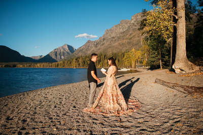 couple stands at lake mcdonald at sunset reading vows at their wedding
