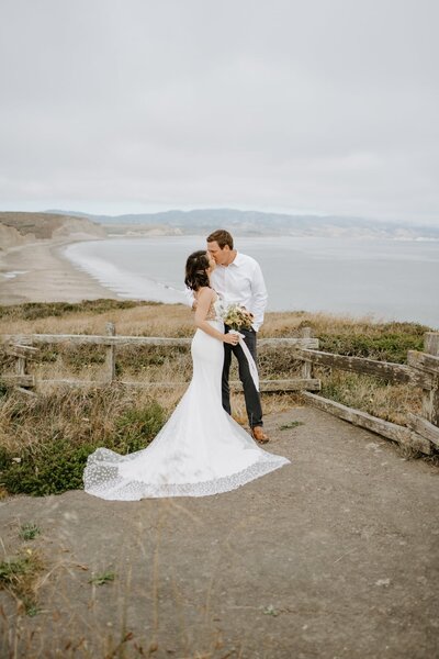 Elopement couple kissing on cliff overlooking the California Coast