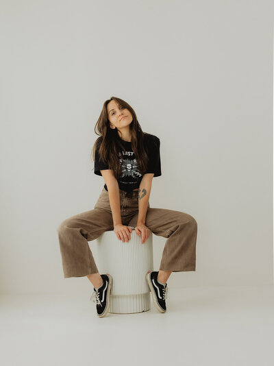 girl sitting relaxed on white stool in photo studio