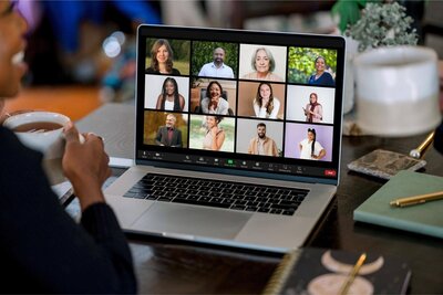 Cyndi participates in a virtual group session on a laptop with diverse individuals smiling on a Zoom call.