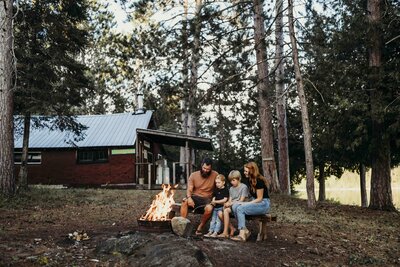 family sitting around campfire in the woods