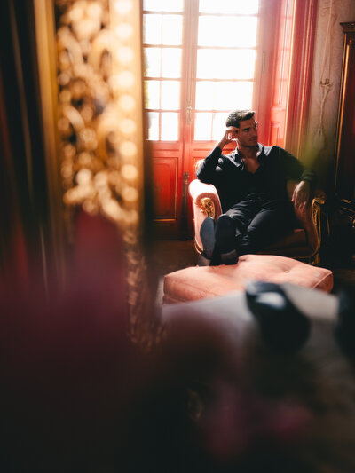 A man embraces in a dimly lit room with soft window light, creating an intimate atmosphere.