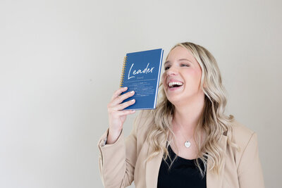 Becca smiling as she playfully holds a book up to her face