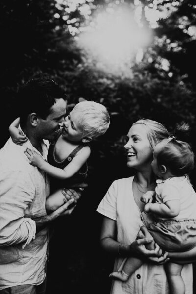 föräldrar håller barn i famnen och skrattar tillsammans under familjefotografering