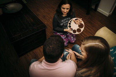 Midwife teaching expectant couple about cervical dilation using a wooden chart during a home birth consultation
